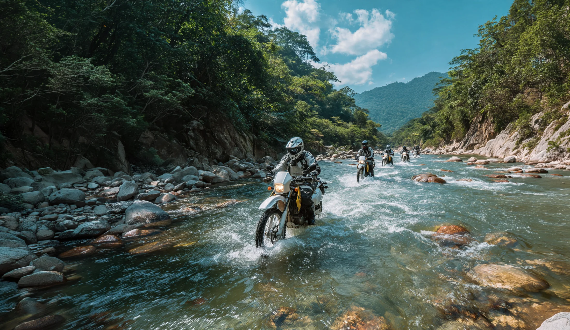 Riders crossing a rocky jungle river on dirt bikes